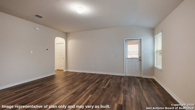 empty room with lofted ceiling, dark hardwood / wood-style floors, and a textured ceiling