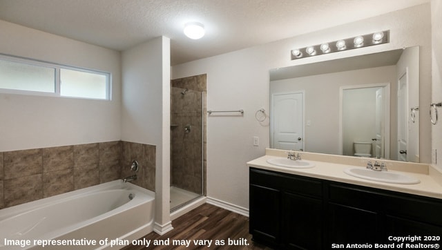 full bathroom featuring a textured ceiling, independent shower and bath, wood-type flooring, toilet, and vanity