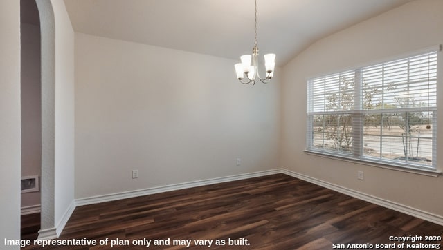 spare room with a chandelier, dark wood-type flooring, and vaulted ceiling