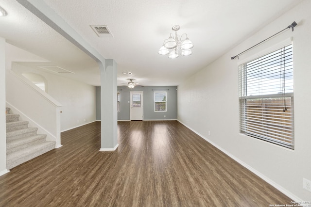 unfurnished living room with dark wood-type flooring, a textured ceiling, and ceiling fan with notable chandelier