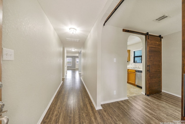 hallway featuring a barn door, sink, and wood-type flooring