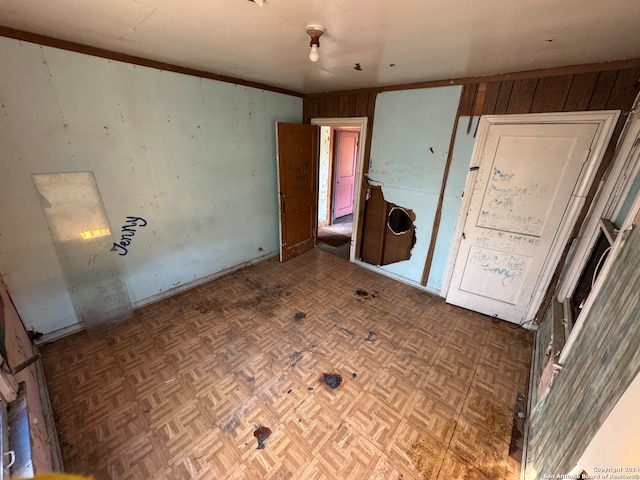 unfurnished bedroom with parquet flooring and wooden walls