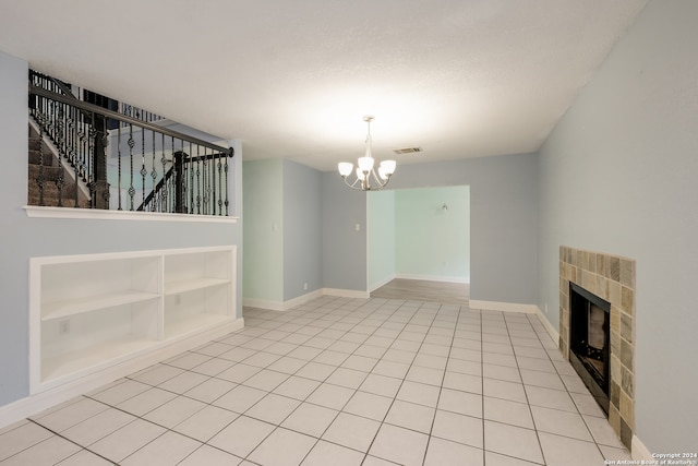 unfurnished living room with an inviting chandelier, built in shelves, a fireplace, and light tile patterned floors