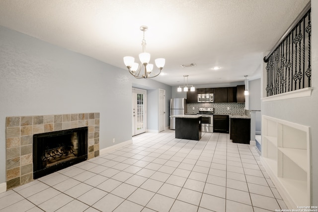 kitchen featuring a kitchen island, a tiled fireplace, backsplash, decorative light fixtures, and appliances with stainless steel finishes