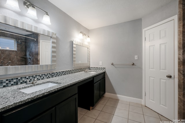 bathroom featuring tasteful backsplash, a tile shower, a textured ceiling, vanity, and tile patterned flooring