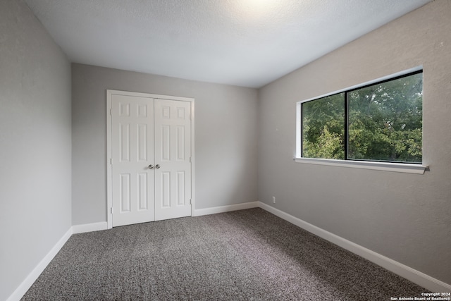 unfurnished bedroom with a closet, a textured ceiling, and carpet floors