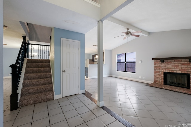 interior space featuring vaulted ceiling with beams, ceiling fan, light tile patterned flooring, and a brick fireplace