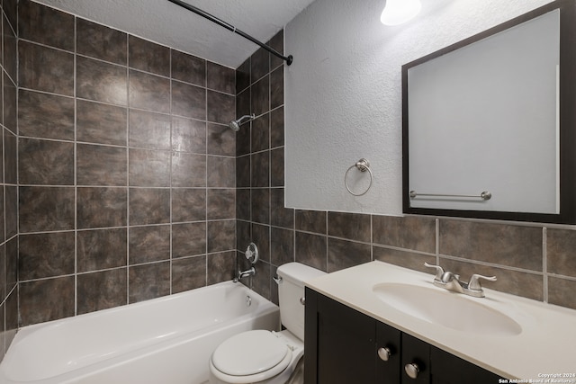 full bathroom with a textured ceiling, toilet, tile walls, tiled shower / bath, and vanity