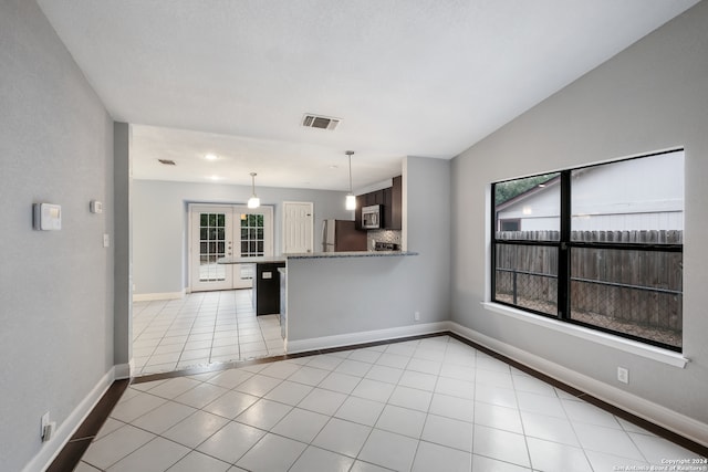 interior space with lofted ceiling, french doors, a healthy amount of sunlight, and light tile patterned floors