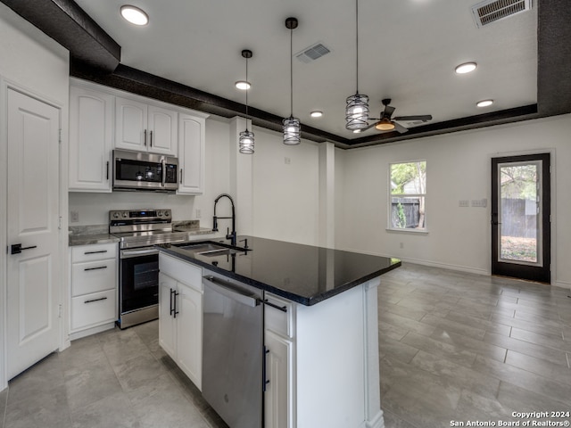 kitchen featuring an island with sink, hanging light fixtures, ceiling fan, stainless steel appliances, and white cabinets