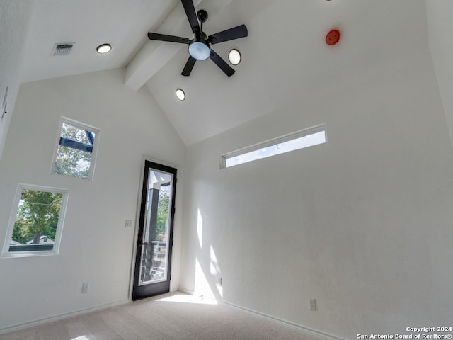 carpeted empty room with beamed ceiling, high vaulted ceiling, and plenty of natural light