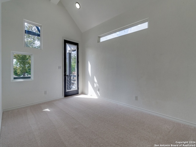 spare room featuring high vaulted ceiling and light colored carpet