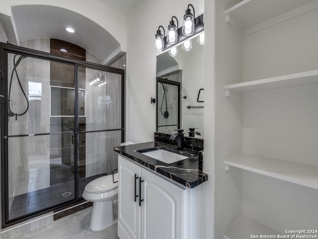 bathroom featuring vanity, toilet, a shower with shower door, and tile patterned flooring