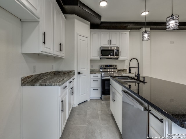 kitchen featuring white cabinetry, stainless steel appliances, sink, and decorative light fixtures