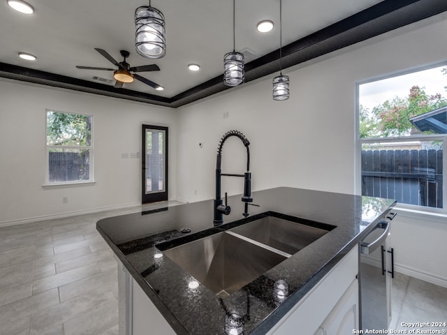 kitchen featuring white cabinetry, sink, dark stone counters, and pendant lighting