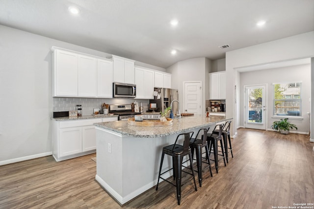 kitchen featuring light hardwood / wood-style flooring, white cabinets, a kitchen island with sink, and stainless steel appliances