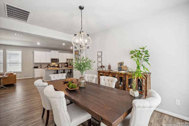 dining space featuring sink, dark wood-type flooring, and a chandelier