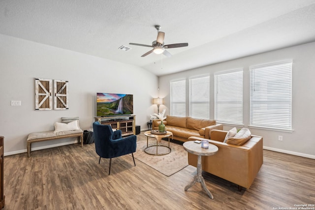 living room featuring hardwood / wood-style floors, vaulted ceiling, a textured ceiling, and ceiling fan