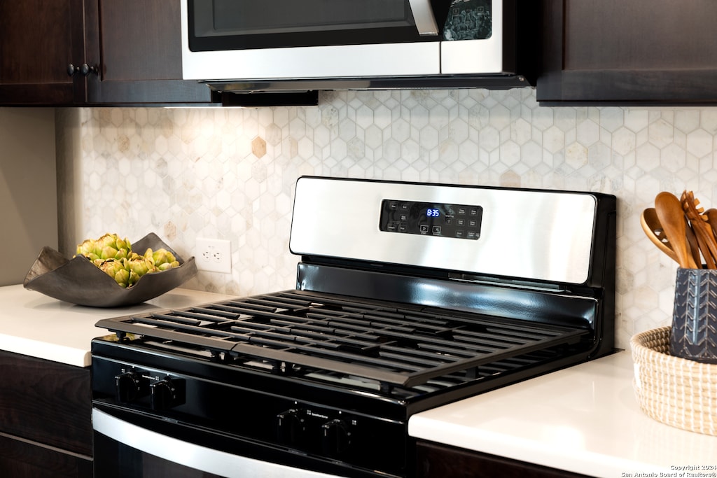 kitchen featuring dark brown cabinets, gas stove, and tasteful backsplash