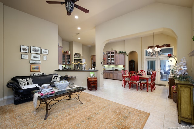 tiled living room featuring high vaulted ceiling and ceiling fan with notable chandelier