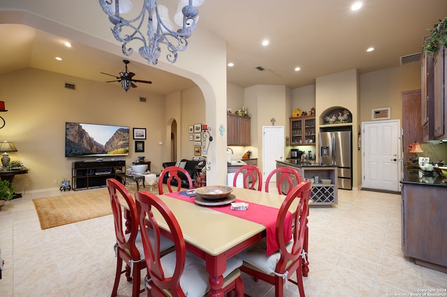 tiled dining space featuring lofted ceiling and ceiling fan with notable chandelier