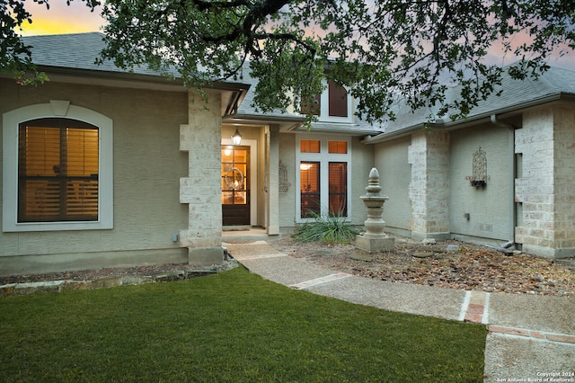 exterior entry at dusk featuring a yard