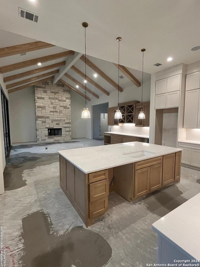 kitchen with white cabinetry, a spacious island, light stone countertops, lofted ceiling with beams, and decorative light fixtures