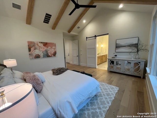 bedroom with a barn door, high vaulted ceiling, beam ceiling, and light wood-type flooring