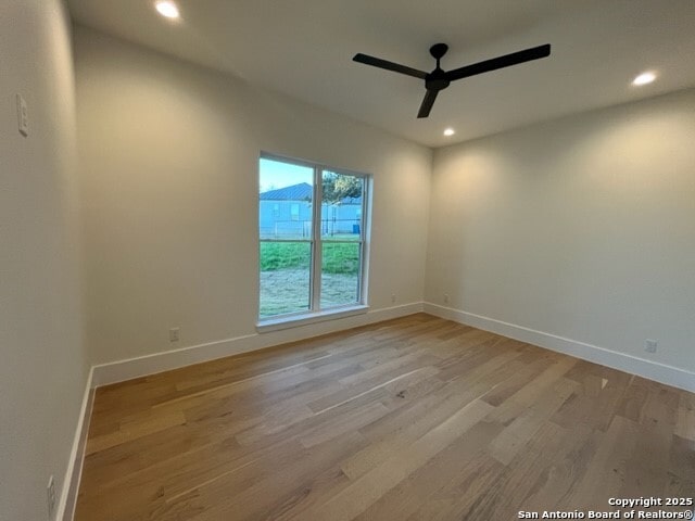 empty room with ceiling fan and light hardwood / wood-style floors