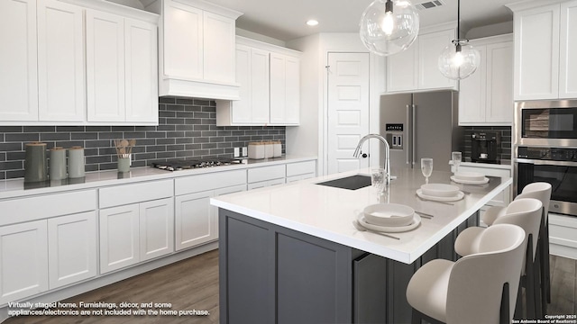 kitchen with recessed lighting, a sink, a kitchen bar, dark wood-type flooring, and appliances with stainless steel finishes
