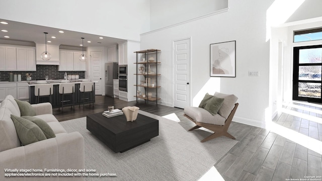 living area with recessed lighting, a high ceiling, baseboards, and dark wood finished floors