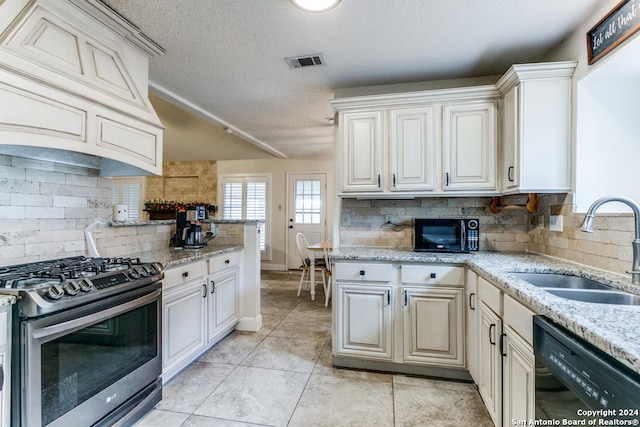 kitchen featuring tasteful backsplash, a textured ceiling, light tile patterned flooring, black appliances, and sink