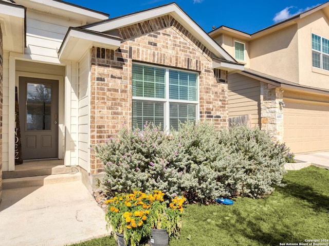 view of exterior entry featuring a yard and a garage