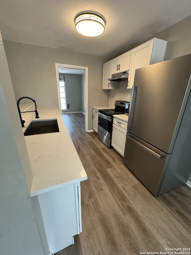 kitchen featuring appliances with stainless steel finishes, white cabinets, hardwood / wood-style flooring, and sink