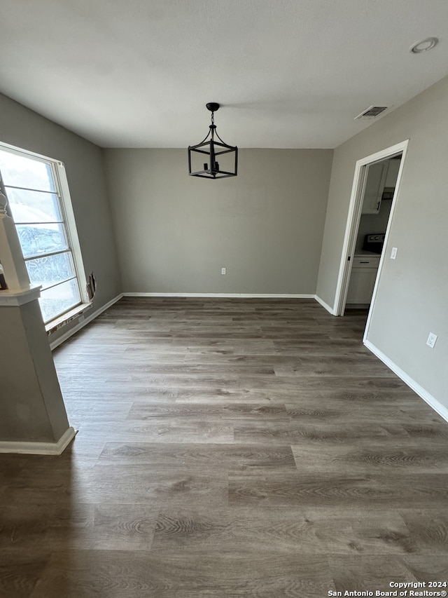 unfurnished dining area with an inviting chandelier and dark wood-type flooring