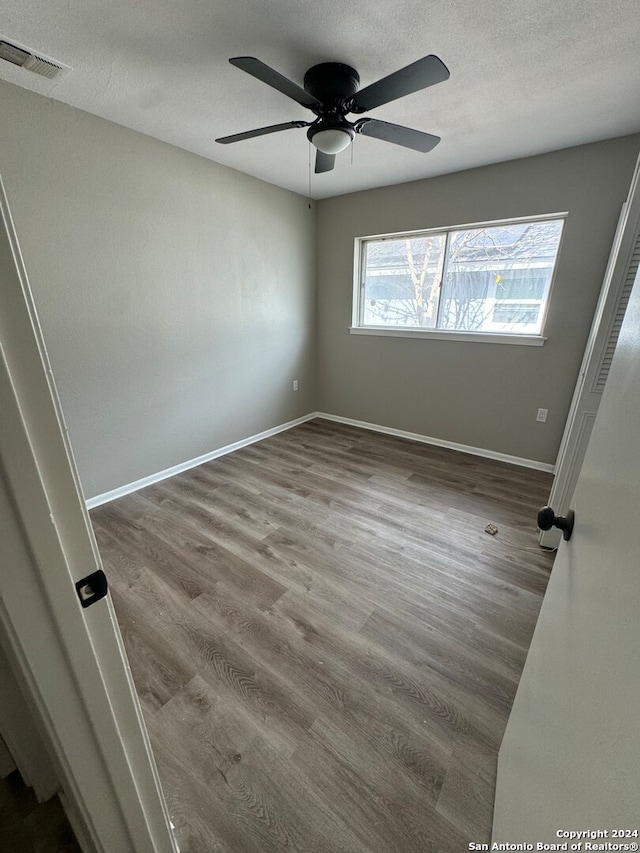 empty room with ceiling fan, hardwood / wood-style flooring, and a textured ceiling