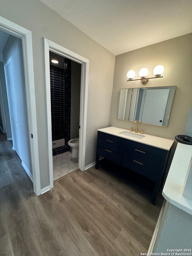 bathroom featuring vanity, toilet, walk in shower, and hardwood / wood-style floors