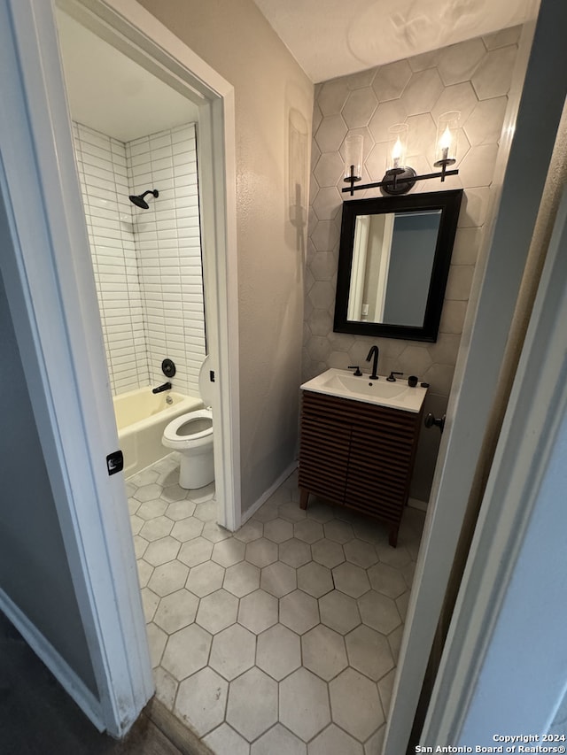 full bathroom featuring decorative backsplash, toilet, tile patterned flooring, tiled shower / bath, and vanity