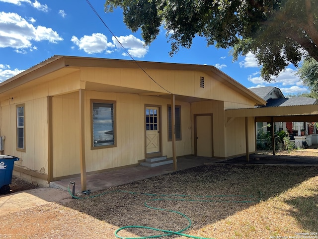 back of house featuring a carport