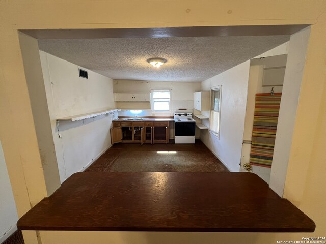 kitchen with sink, white electric range, kitchen peninsula, and a textured ceiling