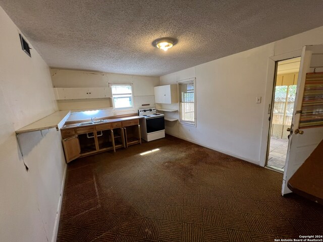 kitchen featuring white electric range oven, a textured ceiling, dark colored carpet, and white cabinets