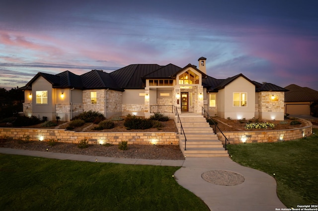 view of front facade featuring metal roof, stone siding, stucco siding, a standing seam roof, and a front yard