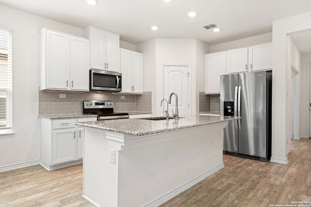 kitchen featuring appliances with stainless steel finishes, an island with sink, and white cabinets