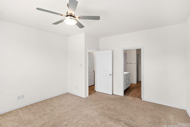 unfurnished bedroom featuring a spacious closet, ceiling fan, ensuite bath, and light colored carpet