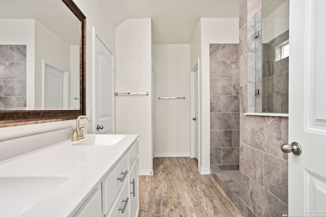 bathroom with vanity, hardwood / wood-style flooring, and tiled shower