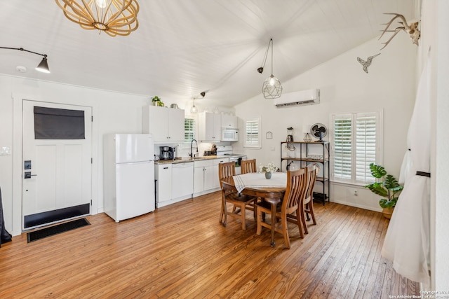 dining area with sink, light hardwood / wood-style floors, lofted ceiling, and a wall unit AC