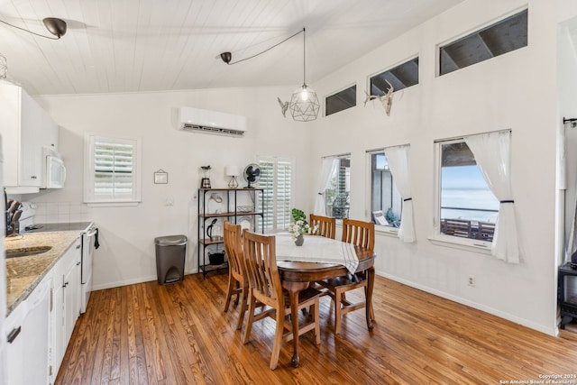 dining room with a wall mounted AC, vaulted ceiling, light hardwood / wood-style floors, and a healthy amount of sunlight