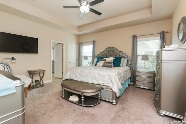 bedroom with ceiling fan, a raised ceiling, multiple windows, and carpet floors