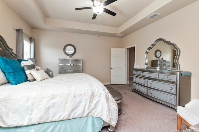 carpeted bedroom featuring a raised ceiling and ceiling fan