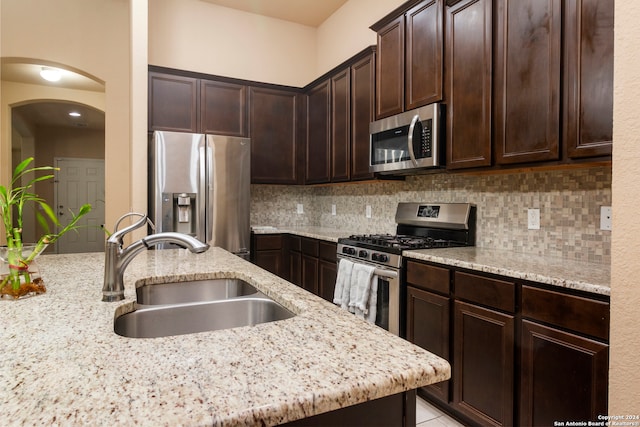 kitchen featuring light stone counters, appliances with stainless steel finishes, sink, and dark brown cabinets